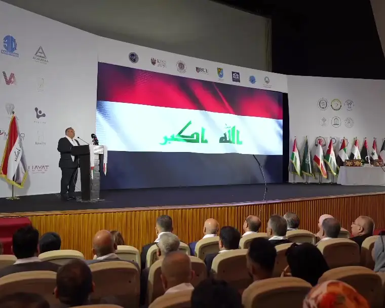 منصة حفل افتتاح مؤتمر UNC IDC وعلى الشاشة العلم العراقي